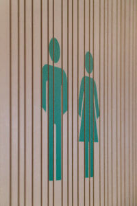 Piktogramme für männlich und weiblich auf Holzoberfläche im Gebäude der Tiroler Versicherung.